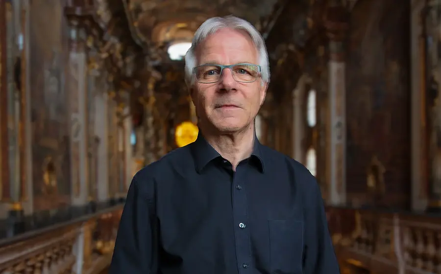 Stefan Moser in einem schwarzen Hemd im Innenraum einer Kirche