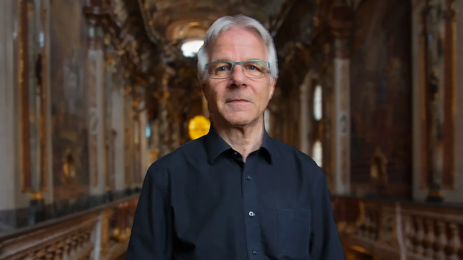 Stefan Moser in einem schwarzen Hemd im Innenraum einer Kirche