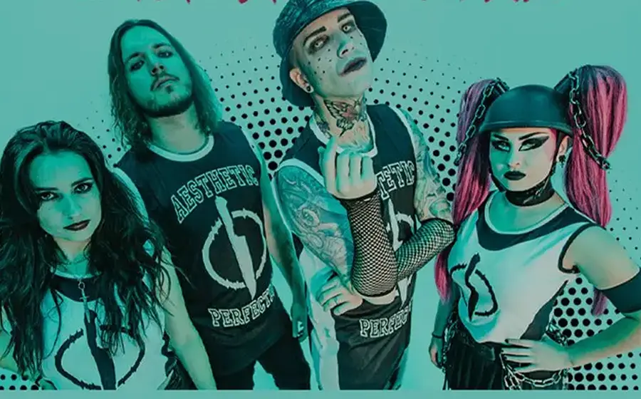 Bandfoto von Aesthetic Perfection. Vier Bandmitglieder in alternativem Bühnenstyling posieren vor türkisfarbenem Hintergrund mit Punktraster, darunter eine Person mit Bucket Hat und Tätowierungen sowie eine Person mit pinken Zöpfen und schwarzer Kopfbedeckung.