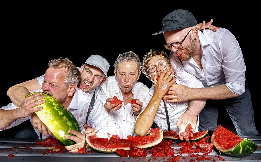 Foto der Musikgruppe 5/8erl in Ehr’n – 20 Jahre Wiener Soul, mit den Bandmitgliedern beim Wassermelone-Essen