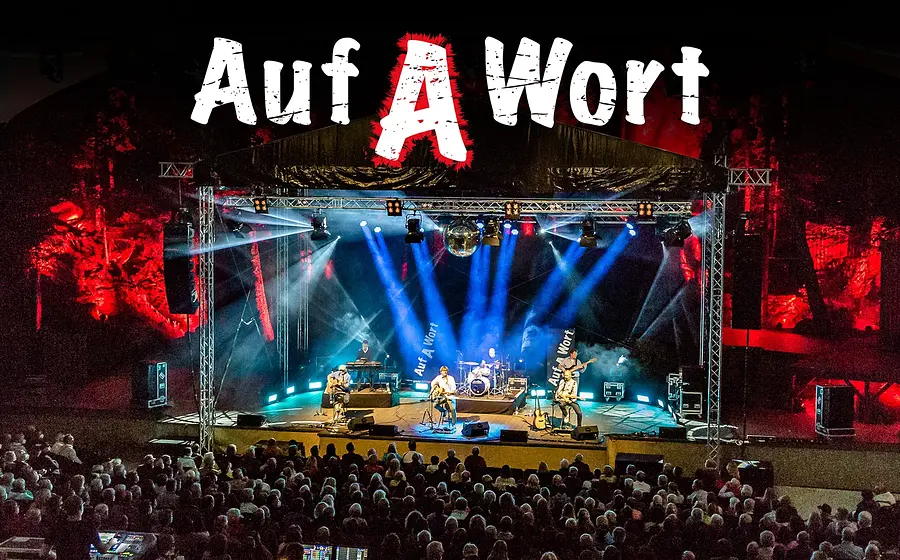 Bühnenfoto von STS mit fünf Musikern auf einer großen Open-Air-Bühne vor Publikum, beleuchtet von blauen und roten Scheinwerfern, eine Discokugel, darüber der große Schriftzug Auf A Wort