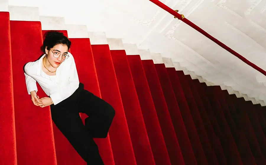 Ana Lucia sitzt auf einer Treppe mit rotem Teppich