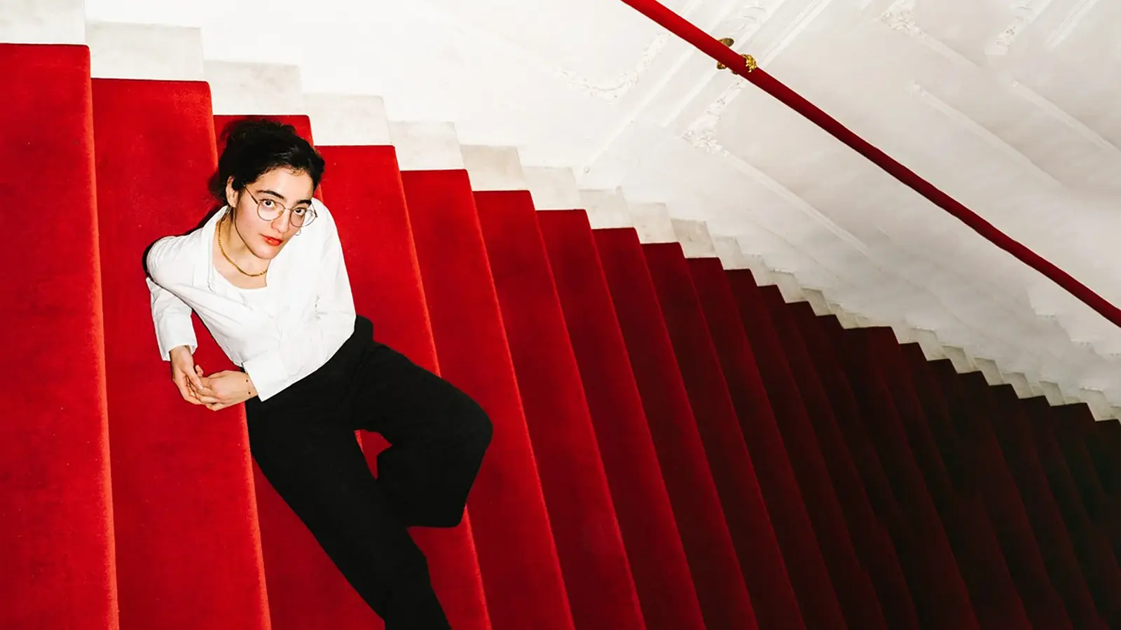 Ana Lucia sitzt auf einer Treppe mit rotem Teppich