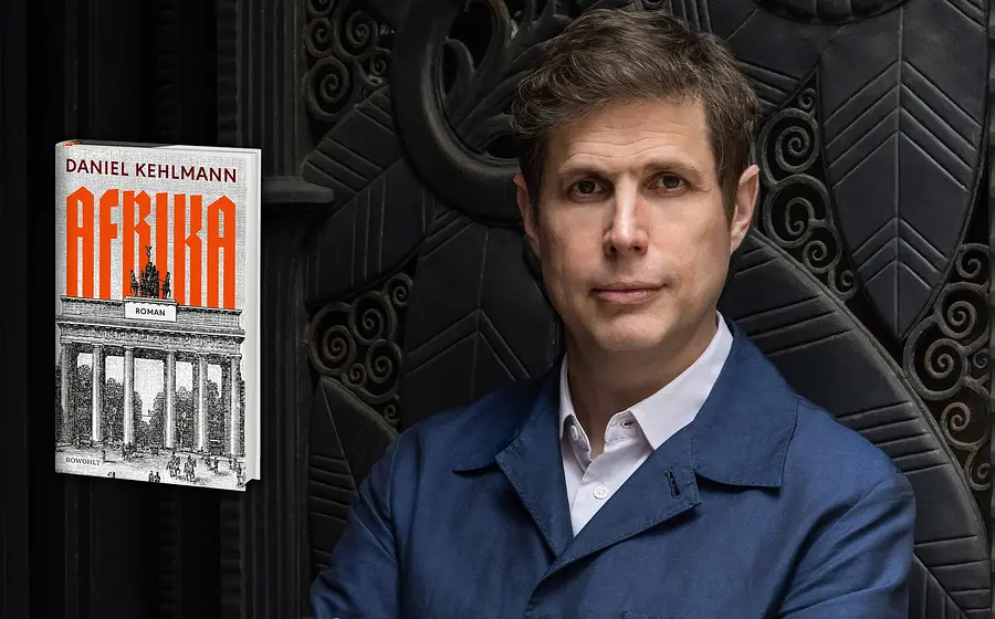 Daniel Kelhmann in blauem Sakko und weißem Hemd vor einer dunkel verzierten Wand, daneben das Buchcover des Romans Lichtspiel mit orangefarbenem Titel und Darstellung des Brandenburger Tors.