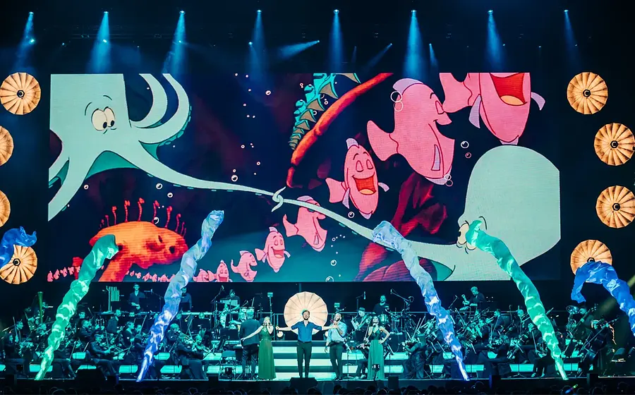 Orchester vor Leinwand auf der viele Tickfilm-Fische zu sehen sind