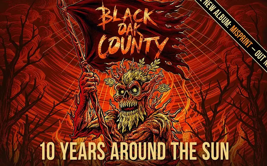 Plakatmotiv von Black Oak County mit den Aufschriften Black Oak County, 10 Years Around The Sun Im Zentrum steht eine düstere baumartige Kreatur mit Fahne vor einer rot orangefarbenen Waldkulisse mit Flammen und kahlen Bäumen.