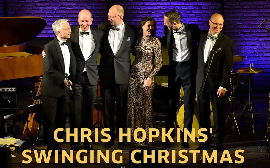Sechs elegant gekleidete Musikerinnen und Musiker stehen Arm in Arm auf einer Bühne vor Instrumenten und Backsteinwand, darunter der Schriftzug Chris Hopkins – Swinging Christmas  in gelb