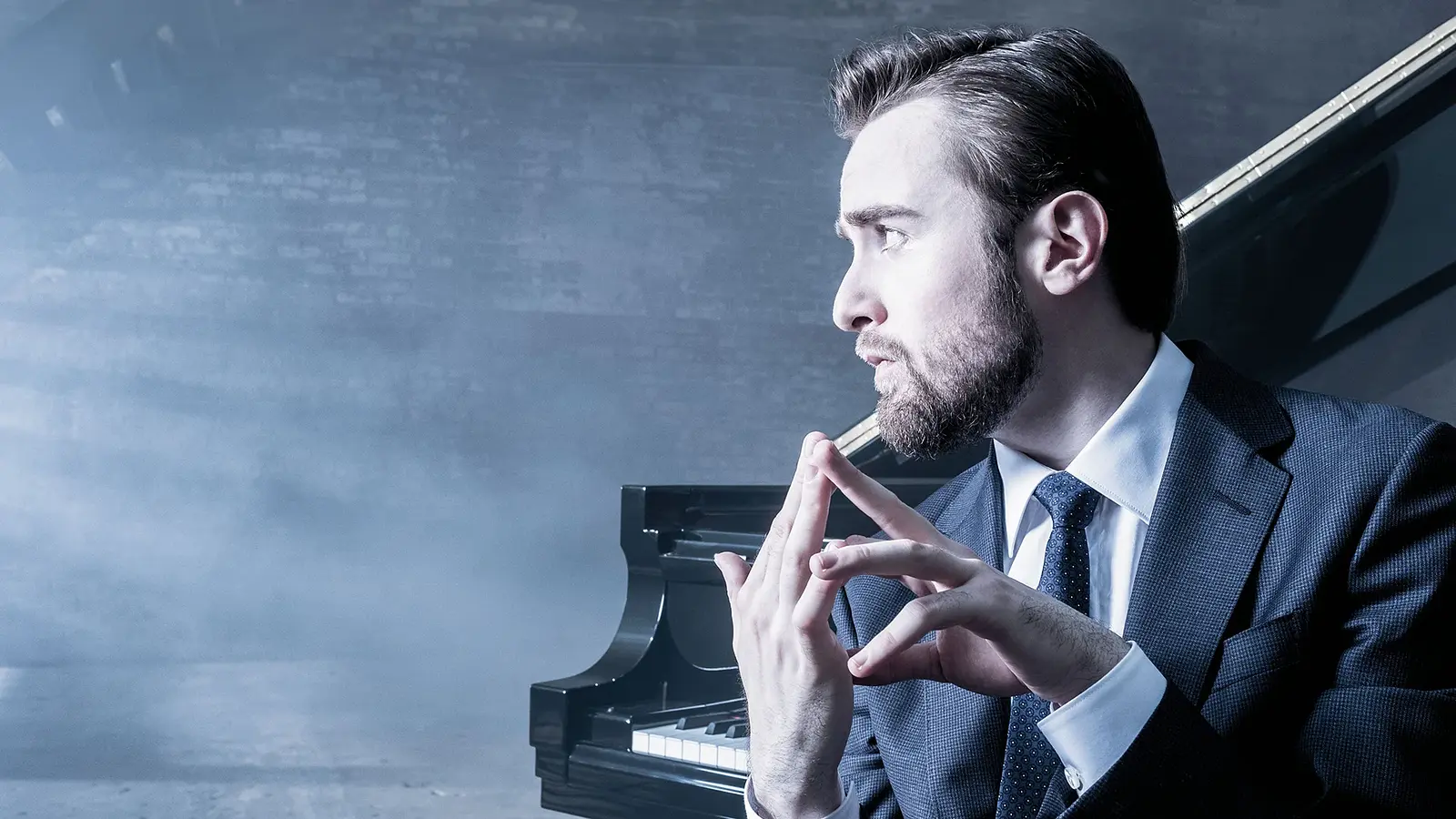 Promobild für das Event ‚Daniil Trifonov & Berliner Barocksolisten‘: Eine Person im dunklen Anzug sitzt vor einem Flügel in einem neblig beleuchteten Raum und hält die Hände vor dem Instrument