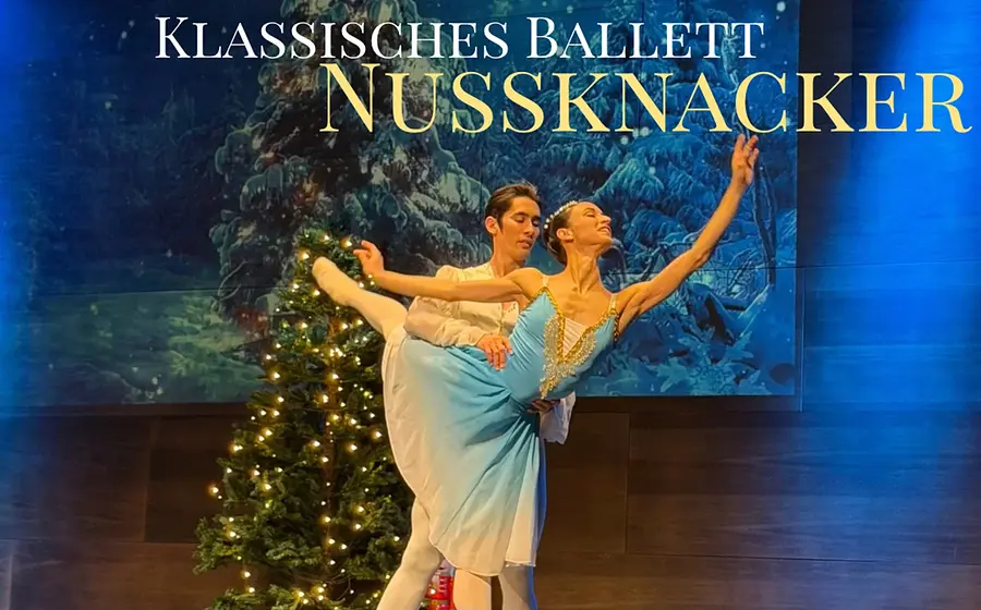 Klassisches Ballett „Nussknacker“: Zwei Tänzer führen eine elegante Pas de deux auf der Bühne vor, weihnachtliche Kulisse mit beleuchtetem Tannenbaum im Hintergrund.