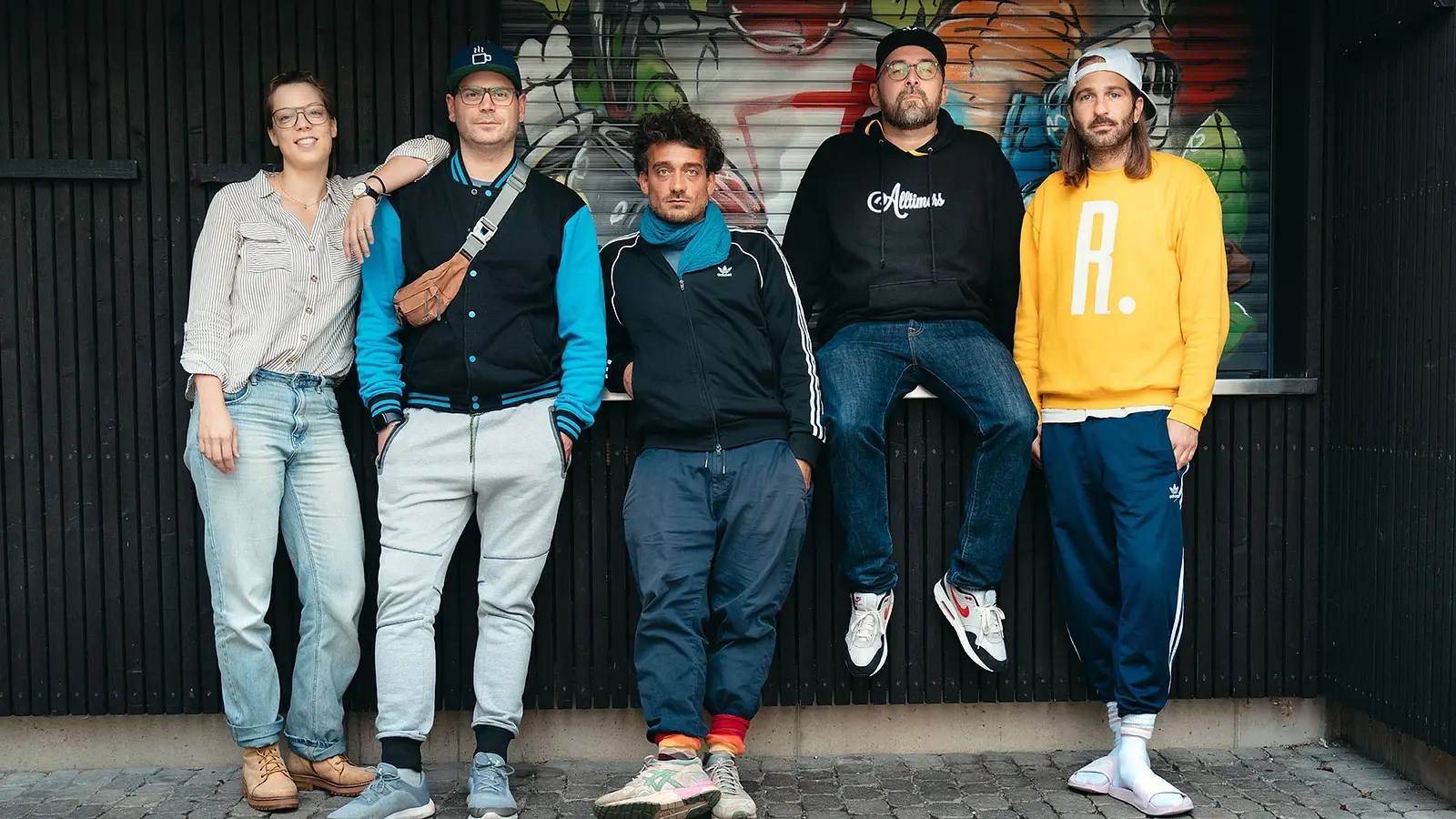 Band dicht & ergreifend vor Graffiti-Wand in urbaner Straße