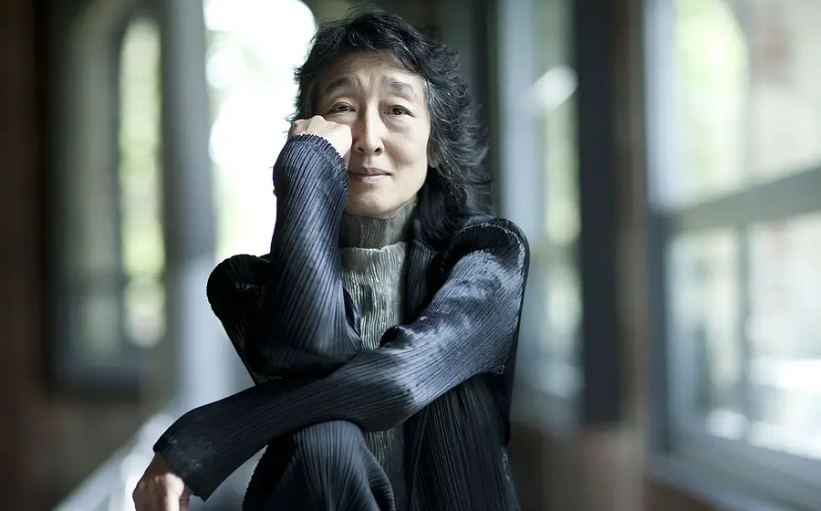 Porträt der Pianistin Mitsuko Uchida in Innenraum vor Fensterfront.