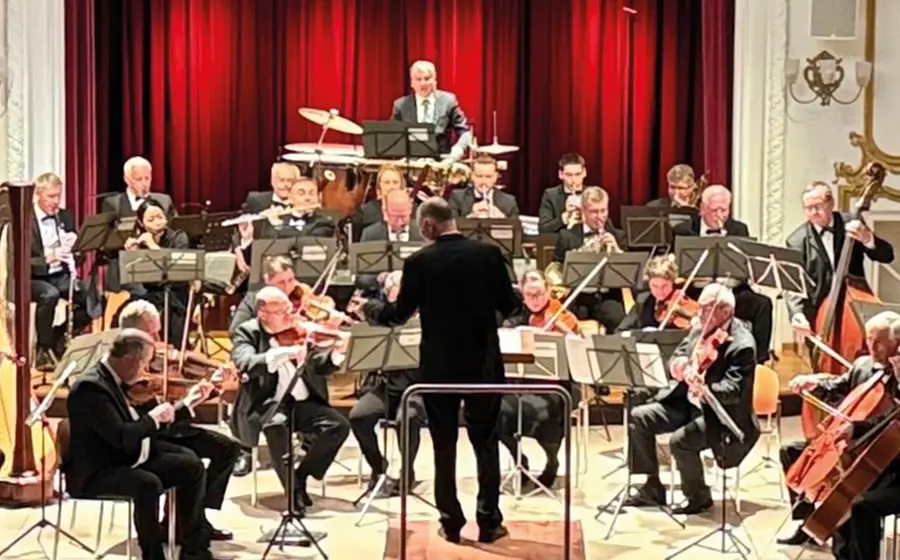 Ein Orchester auf einer Bühne vor einem roten Vorhang