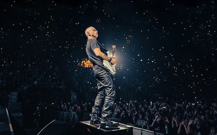 Eros Ramazotti steht auf der Bühne mit seiner Gitarre und performt für eine ausverkaufte Arena.