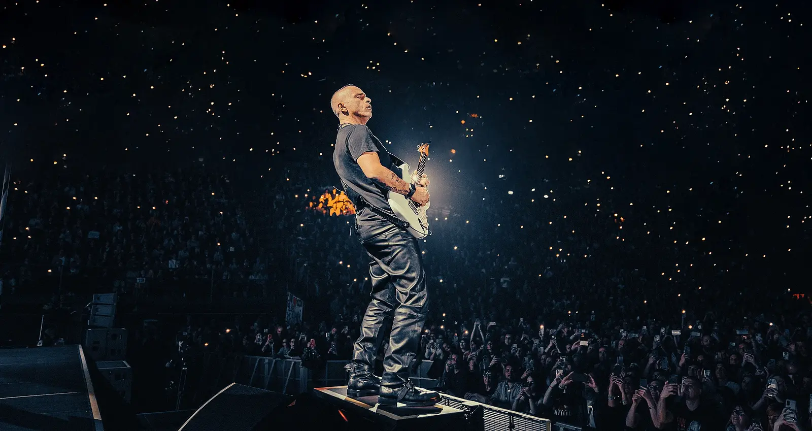 Eros Ramazotti steht auf der Bühne mit seiner Gitarre und performt für eine ausverkaufte Arena.
