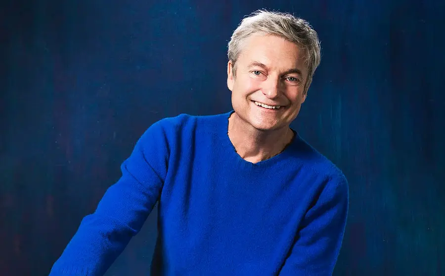 Foto des Künstlers mit blauem Pullover vor blauem Hintergrund.