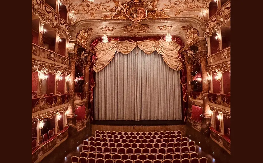 EIn Bild der Bühne des Cuvilliés-Theaters mit Logen und Sitzreihen bei geschlossenem Bühnenvorhang