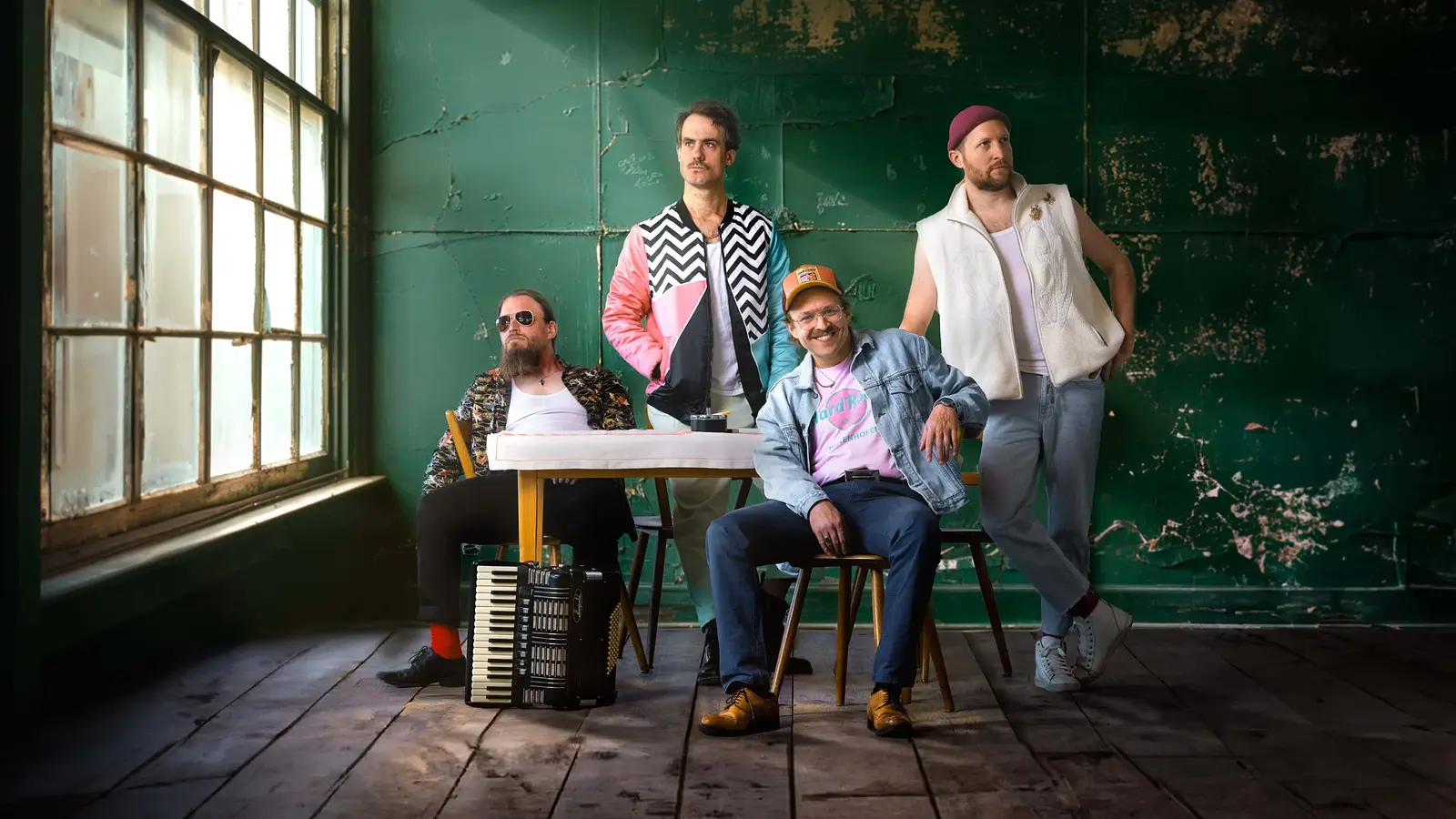 die Band Gankino Circus in einem Raum mit alten Fenstern in dunklem Licht vor einer türkisgrünen Wand