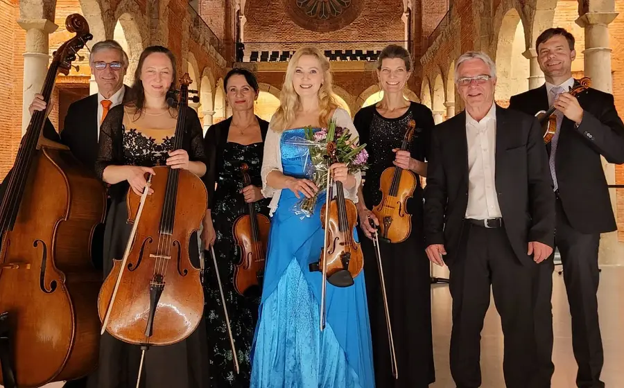 Foto des Orchesters mit Instrumenten vor historischer Kulisse