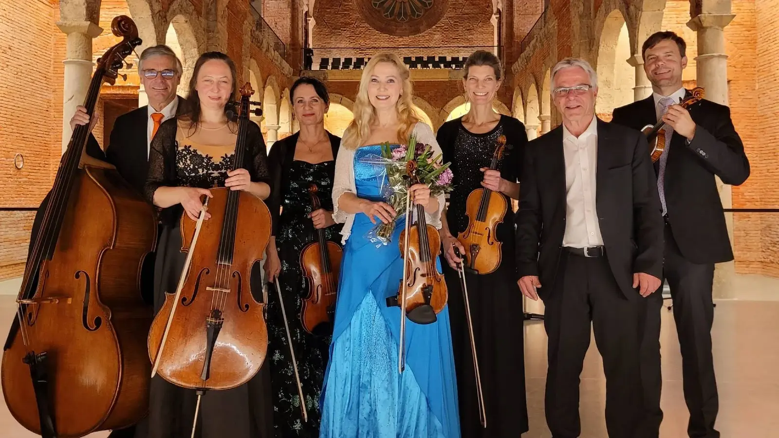 Foto des Orchesters mit Instrumenten vor historischer Kulisse