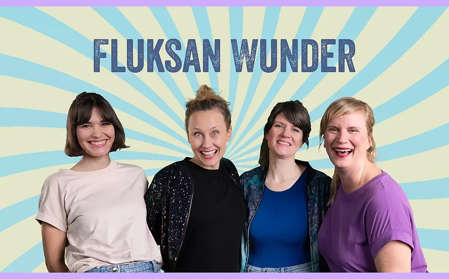 Vier Frauen der Musikgruppe Fluksan Wunder stehen lächelnd vor einem hellgelben Hintergrund mit hellblauen Strahlen. Oberhalb der Gruppe steht der Name FLUKSAN WUNDER in dunkelblauer Schrift.