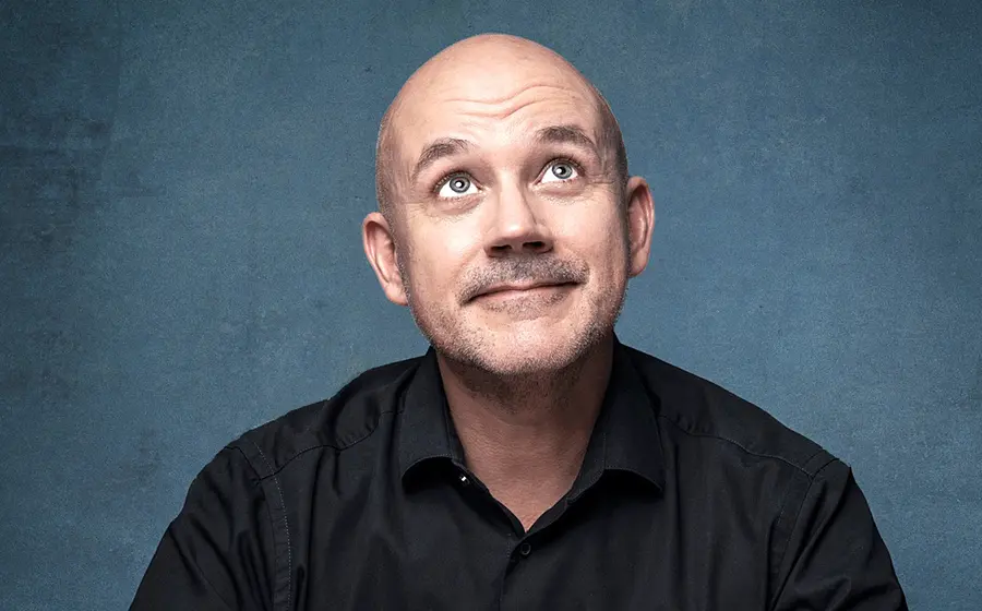 Portrait von Frank Fischer vor einem blauen Hintergrund wie er den Blick nach oben gerichtet hat
