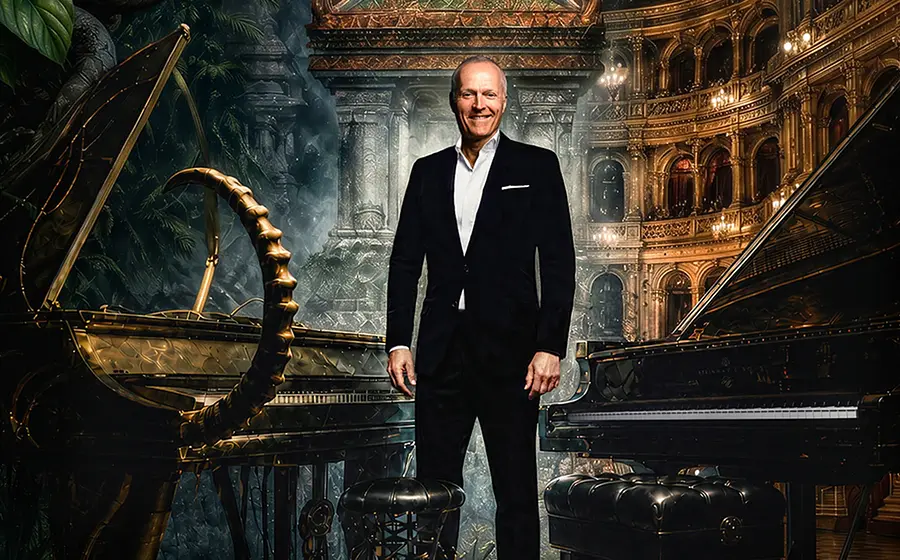 Joja Wendt im dunklen Anzug zwischen zwei Konzertflügeln, vor einer opulenten Theaterkulisse mit Säulen, Logen und warmem Bühnenlicht