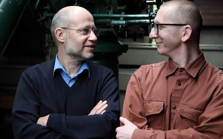Gunkl & Harald Lesch stehen nebeneinander uns sehen sich an und lächeln sich zu