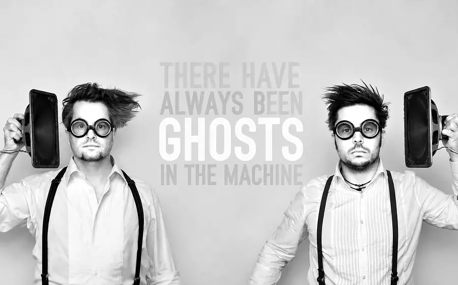 Schwarz-Weiß-Fotomontage mit zwei identisch gekleideten Personen vor hellem Hintergrund. Beide halten Lautsprecher neben dem Kopf und tragen runde Schutzbrillen, in der Bildmitte steht der Schriftzug There Have Always Been Ghosts in the Machine.