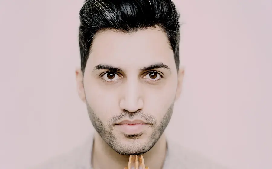 Porträt von Kian Soltani, Cellist, mit seinem Instrument vor hellem Hintergrund.