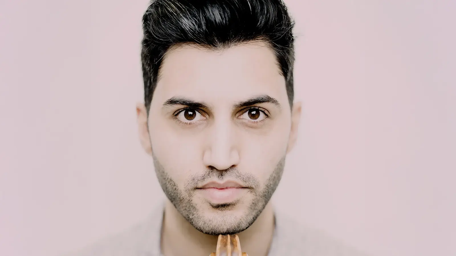 Porträt von Kian Soltani, Cellist, mit seinem Instrument vor hellem Hintergrund.