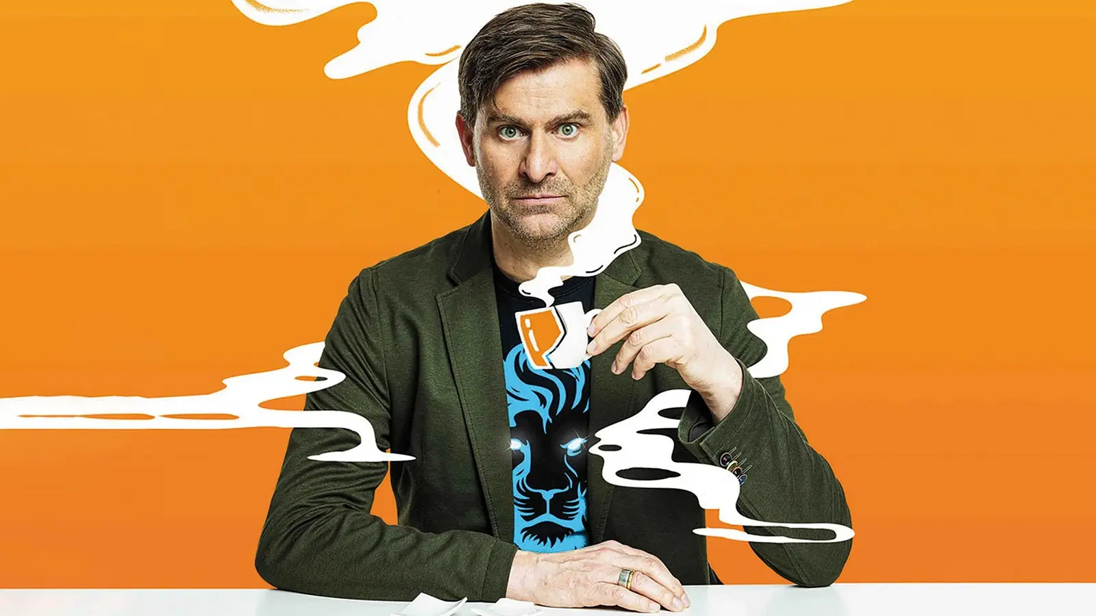 Porträtfoto von Michael Altinger in grünem Sakko und schwarzem T‑Shirt mit blauem Löwenmotiv vor orangefarbenem Hintergrund, sitzend an einem weißen Tisch und eine kleine Kaffeetasse in der Hand haltend, umgeben von grafisch dargestellten weißen Dampfschwaden.
