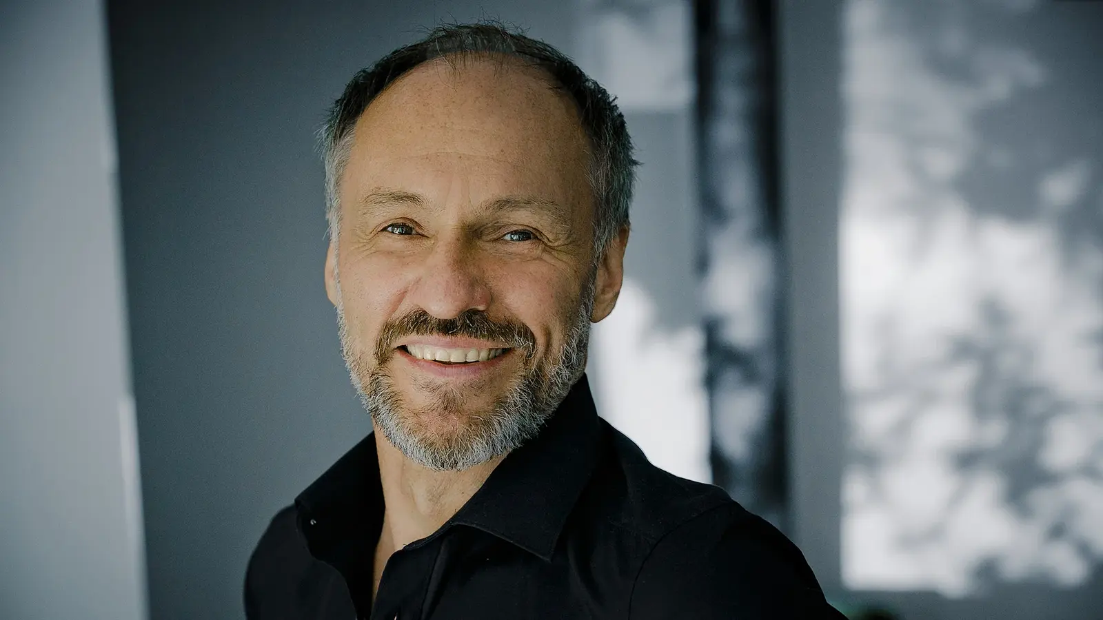 Portrait von Armin Stockerer in schwarzem Hemd vor verschwommenem Hintergrund