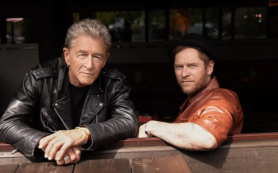 Musikerporträt von Peter Maffay und Johannes Oerding an einem Holztisch im Außenbereich, Lederjacken und urbanes Setting mit natürlichem Licht