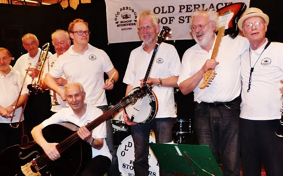 Acht Musiker der Old Perlach Roof Stompers in weissen Shirts und dunklen Hosen mit Instrumenten auf Bühne