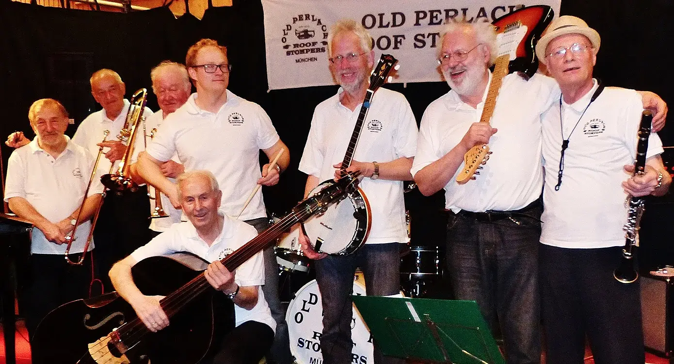 Acht Musiker der Old Perlach Roof Stompers in weissen Shirts und dunklen Hosen mit Instrumenten auf Bühne