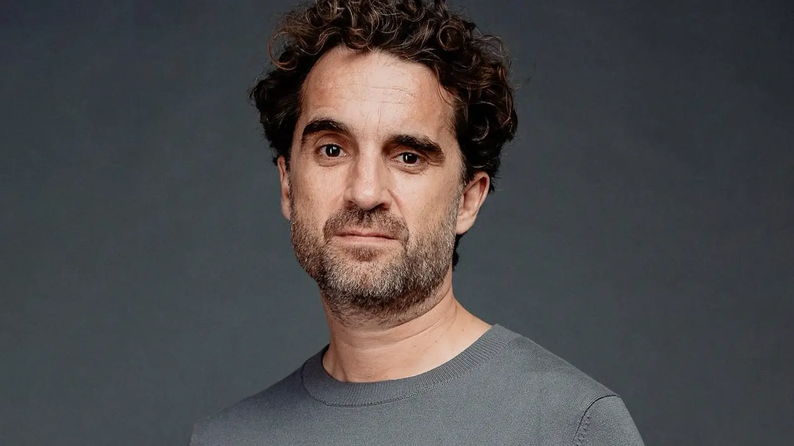 Ein Portrait von Oliver Wnuk in grauem Pullover und grauem Hintergrund