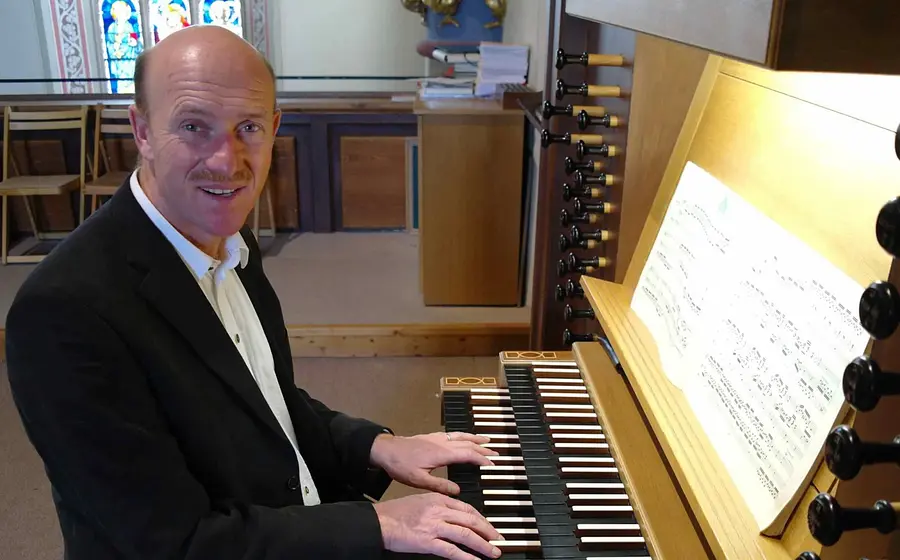 Mann in schwarzem Anzug an Orgel sitzend