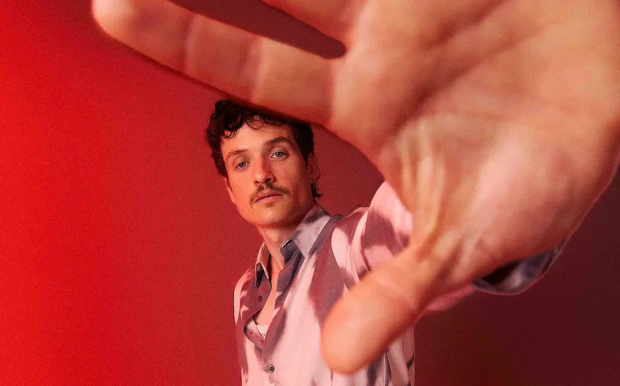 Foto für das Event von PaulWetz mit dem Künstler und der Handfläche im Vordergrund vor rotem Hintergrund.