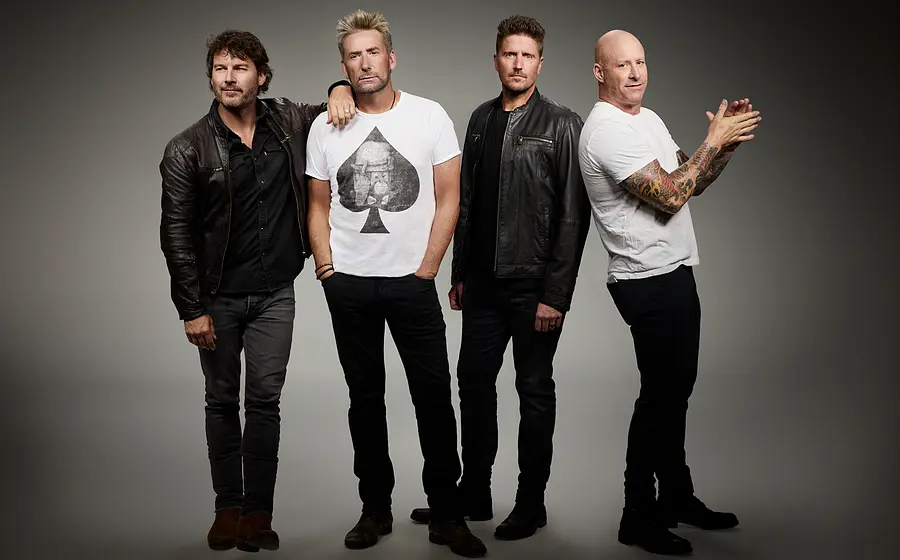 Die vier Bandmitglieder von Nickelback posieren in schwarz-weißer Kleidung vor grauem Hintergrund.