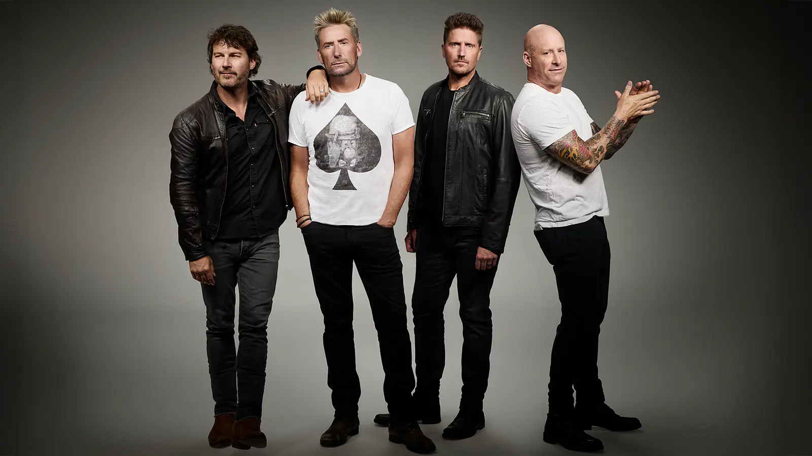 Die vier Bandmitglieder von Nickelback posieren in schwarz-weißer Kleidung vor grauem Hintergrund.