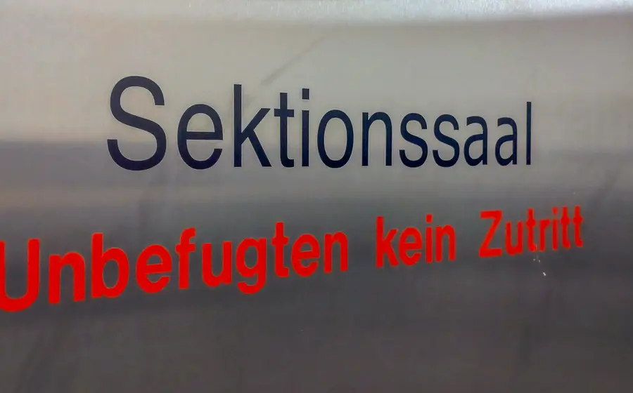 Ein Schild mit der Aufschrift Sektionssaal in schwarz und Unbefugten kein Zutritt in rot