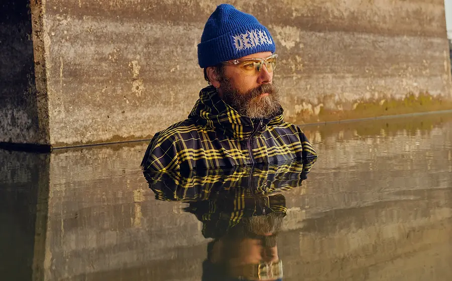 Ein Bild des Künstlers mit blauer Mütze bis zur Brust in Wasser stehend und Spiegelung im Wasser