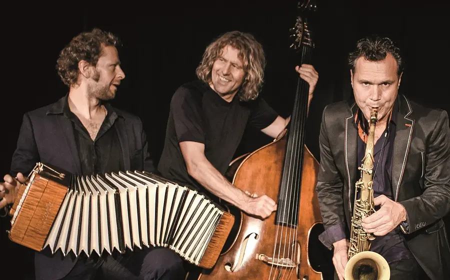 Die Band Quadro Nuevo mit Instrumenten in dunkler Kleidung vor dunklem Hintergrund