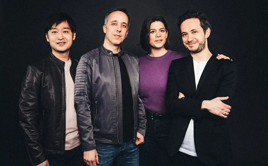 Quatuor Ébène mit vier Musiker:innen in dunkler Kleidung vor schwarzem Hintergrund, nah nebeneinander stehend in einer Studioaufnahme, ohne Instrumente im Bild sichtbar.