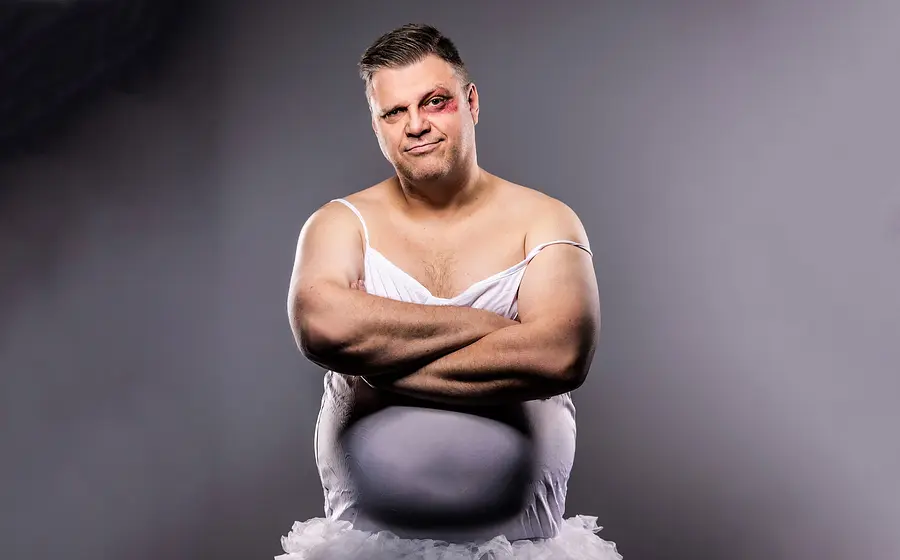 Ralf Winkelbeiner mit blutunterlaufenem Auge in weißem Ballett-Kleid mit grau-nebligem Hintergrund