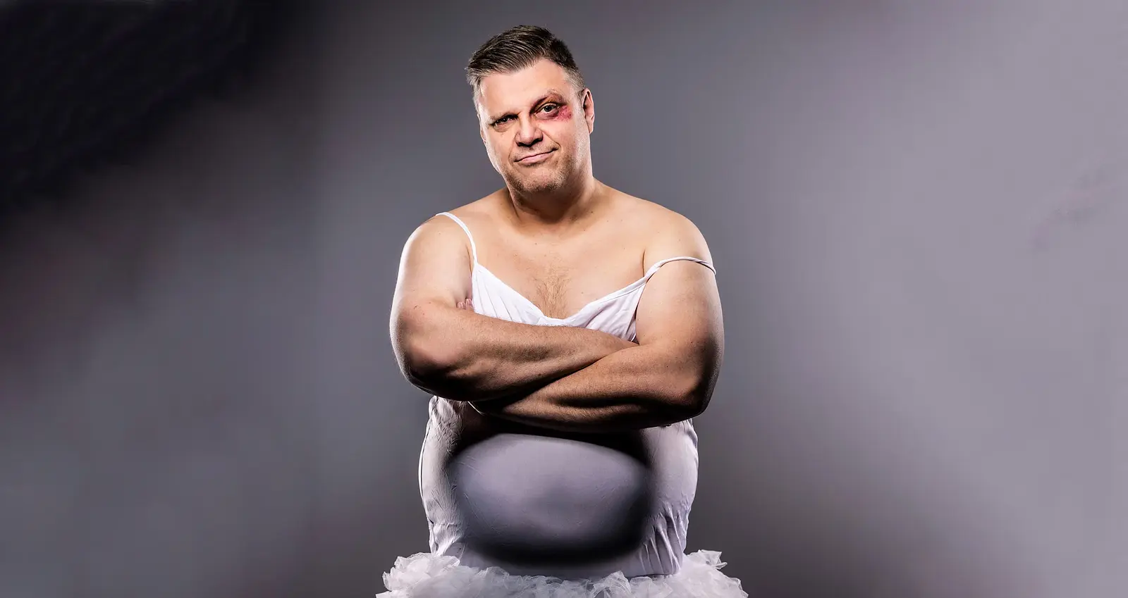 Ralf Winkelbeiner mit blutunterlaufenem Auge in weißem Ballett-Kleid mit grau-nebligem Hintergrund