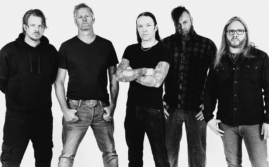 ein schwarz weiss Foto der Band tAKiDA in dunkler Freizeitkleidung vor hellem Hintergrund