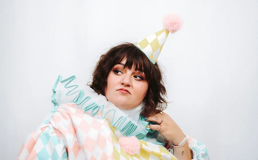 Schwarz-weiß-Foto für die Veranstaltung „Teresa Reichl – Neues Programm“ mit der Künstlerin, verkleidet als Clown, vor weißem Hintergrund.