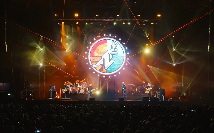 Die Musiker der Australian Pink Floyd Show auf der Bühne mit farbigem Licht und einem großen runden Logo