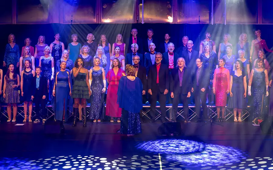 Der Chor Weyhalla mit festlich gekleideten Mitgliedern in lila Bühnenlicht